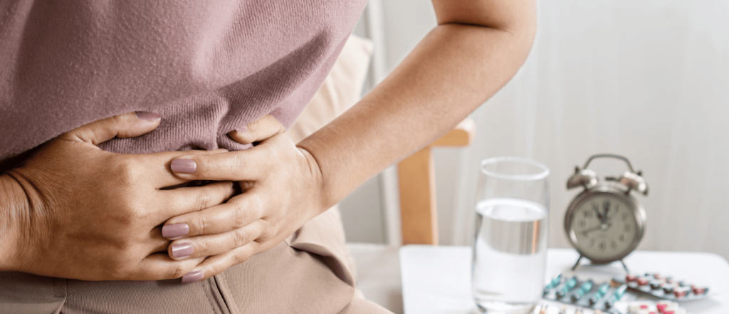 Mujer con las manos en el estómago debido al dolor causante